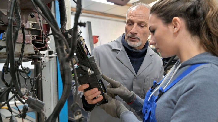 Image showing mentor helping a younger employee understand how to operate a machine..