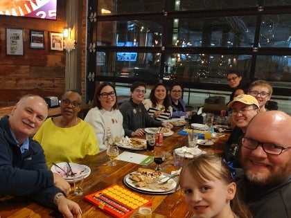 11 Staff members sitting at wooden table at restaurant together