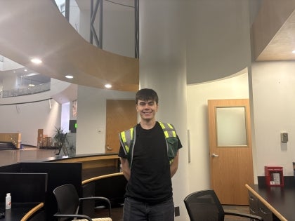 Viking Safety Ambassador wearing green vest and standing behind the student center PD Hub desk