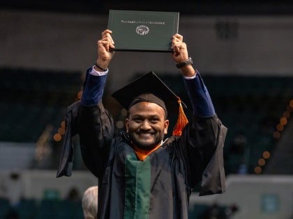 Male graduate holding up his diploma