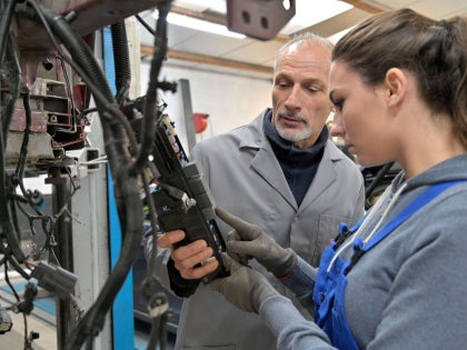 Image showing mentor helping a younger employee understand how to operate a machine..