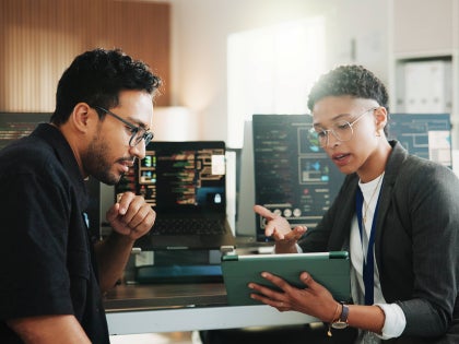 Co--workers at a desk reviewing a computer application