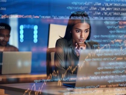 Woman working with technology foreground screen showing code