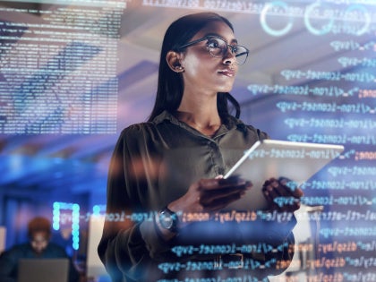 Woman looking at a laptop and large digital screen