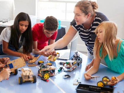 Teacher and elementary students in a classroom working on a project