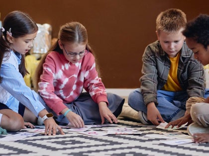 Children sitting on a classroom floor working on an activity together