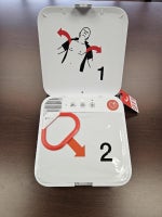 Image of a white AED opened with red and black descriptions on how to operate.